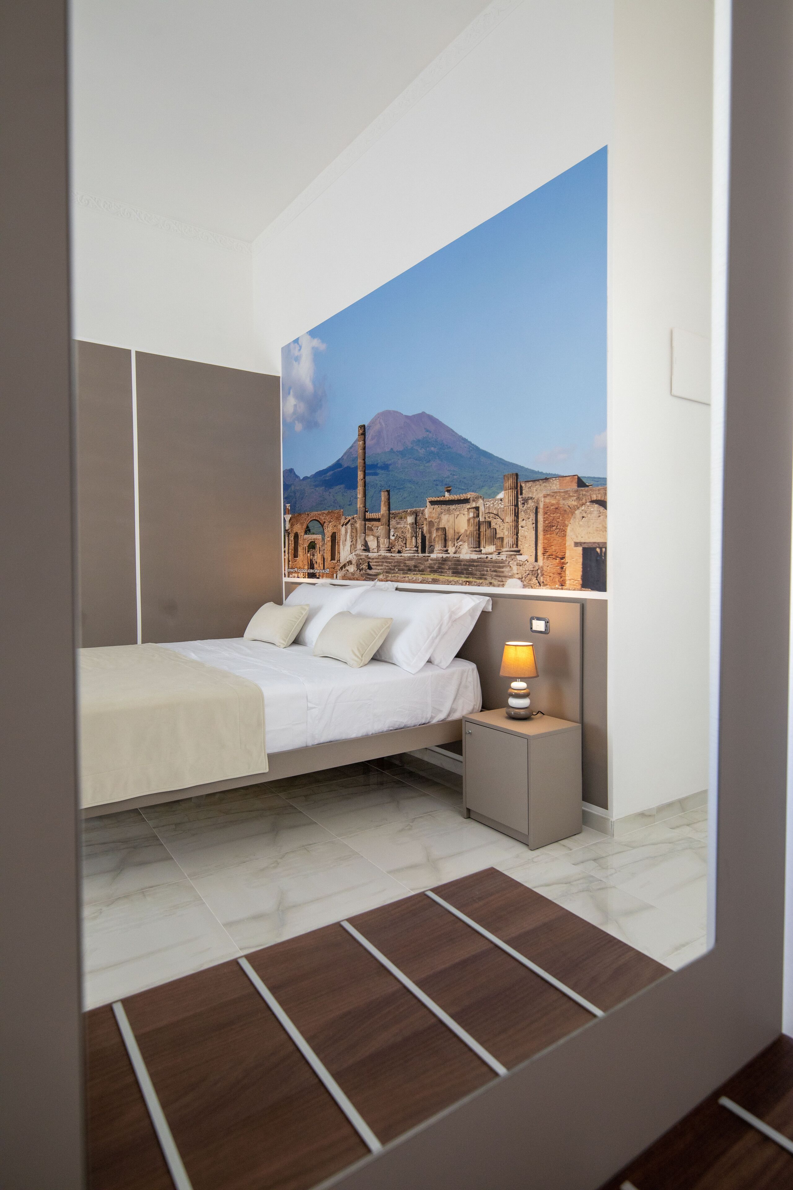 A modern bedroom with a bed, a nightstand, and a painting of a cityscape.