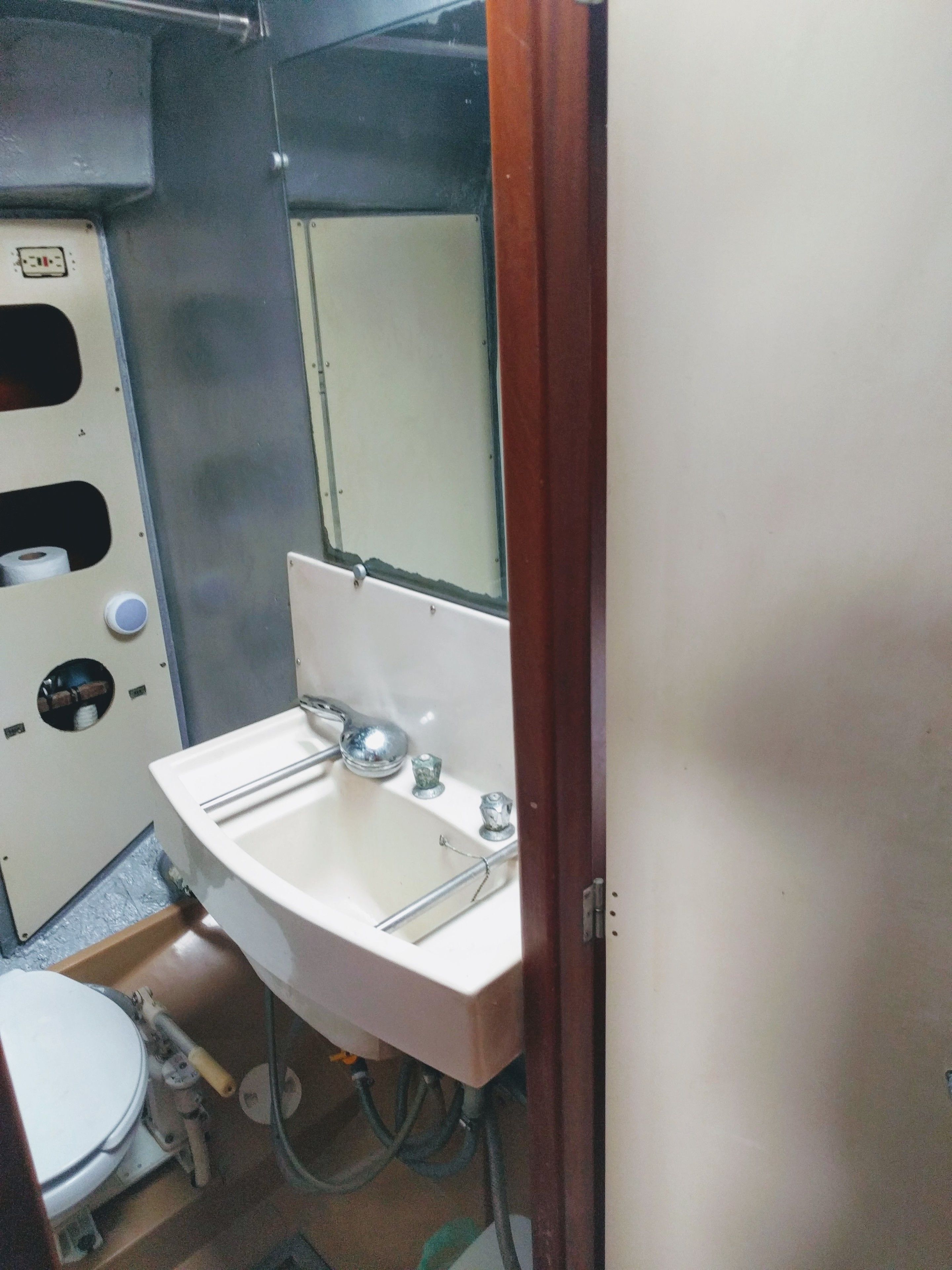 Une petite salle de bain compacte, avec un lavabo blanc, un miroir et des toilettes.