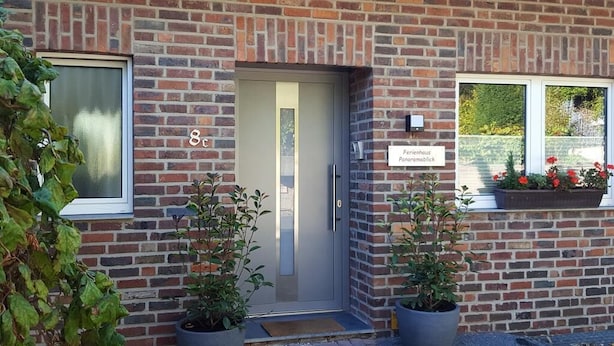 Ein Backsteinhaus mit einer Tür, auf der die Nummer 8 steht, und einem Schild mit der Aufschrift 'Ferienhaus Panoramablick'.