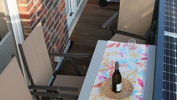 A patio with a table set for two, a grill, and a solar panel.