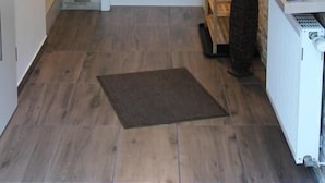 Ein Flur mit einer Steinsäule, einer weißen Tür, einem Heizkörper und einem kleinen Tisch mit Zeitschriften.