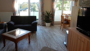 Ein Wohnzimmer mit einer Couch, Couchtisch, Fernseher und einem Essbereich mit Stühlen und Tisch.