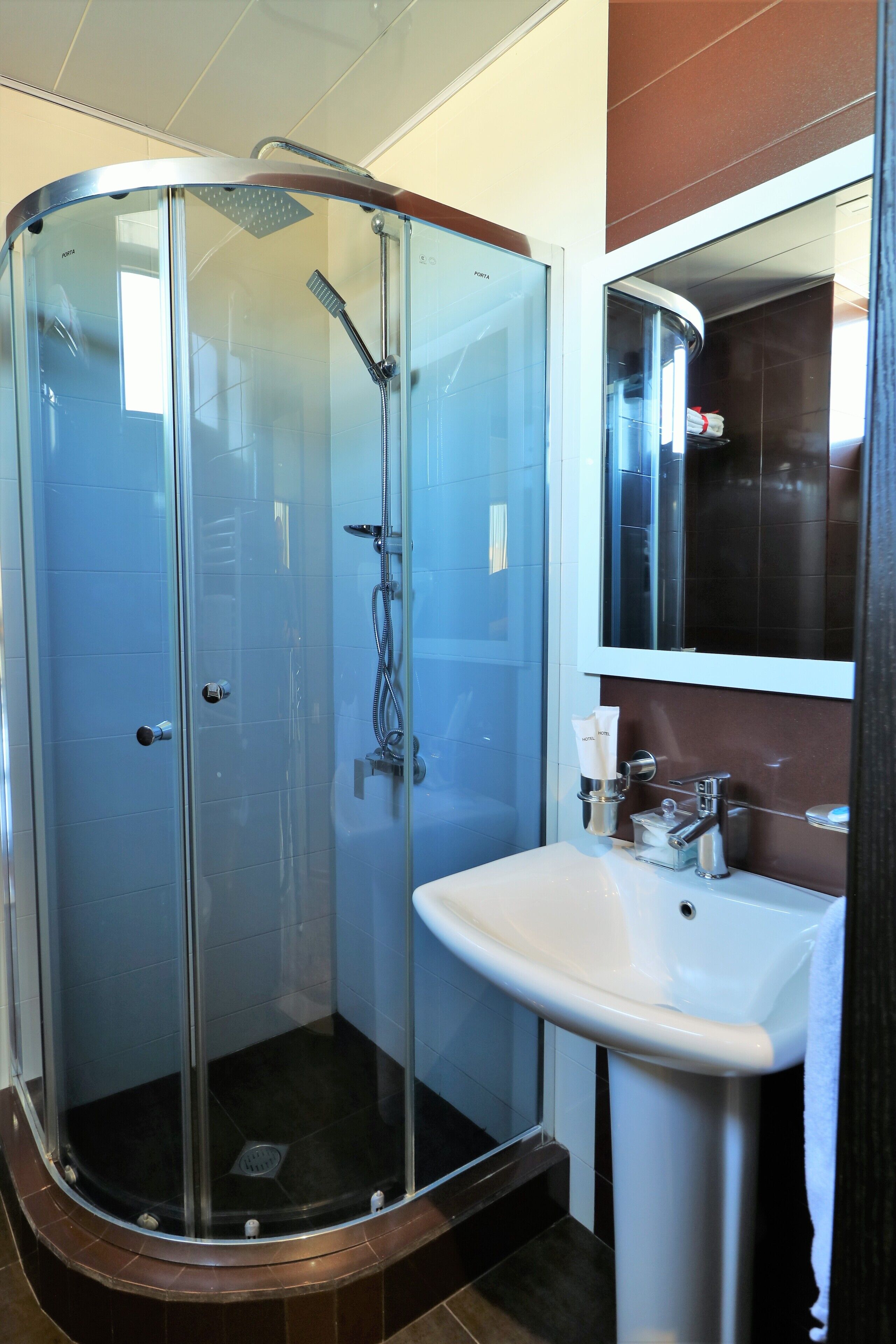 A modern bathroom with a glass-enclosed shower, a white sink, and a mirror above it.