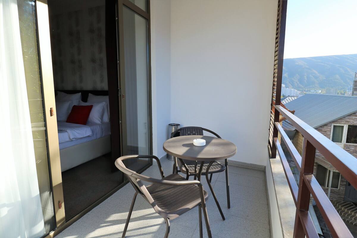 Un balcón con una cama, una mesa y dos sillas.