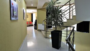 A modern hotel hallway with a staircase, a large potted plant, and artwork on the walls. - East Gate Boutique Hotel (Tbilisi)