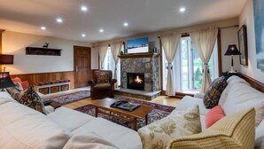 A cozy living room with a stone fireplace, comfortable seating, and a television. - Texas Townhome Condos - 3 Minutes Walk to Gondola by RedAwning (Vail)