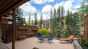 A wooden deck with a table and chairs, a lounge chair, and a spiral staircase. - Texas Townhome Condos - 3 Minutes Walk to Gondola by RedAwning (Vail)