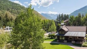 A lodge with a large porch, surrounded by lush greenery and mountains. - Mill Creek Court Condos Just 100 yards from Gondola by RedAwning (Vail)