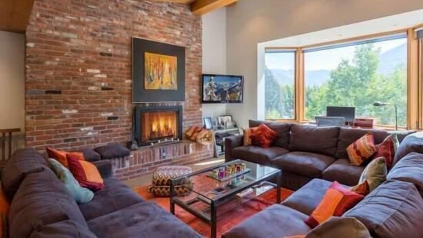 A modern living room with a brick fireplace, a large sectional sofa, and a glass coffee table. - Mill Creek Court Condos Just 100 yards from Gondola by RedAwning (Vail)