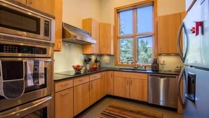 A modern kitchen with stainless steel appliances, wooden cabinets, and a large window providing natural light. - Mill Creek Court Condos Just 100 yards from Gondola by RedAwning (Vail)