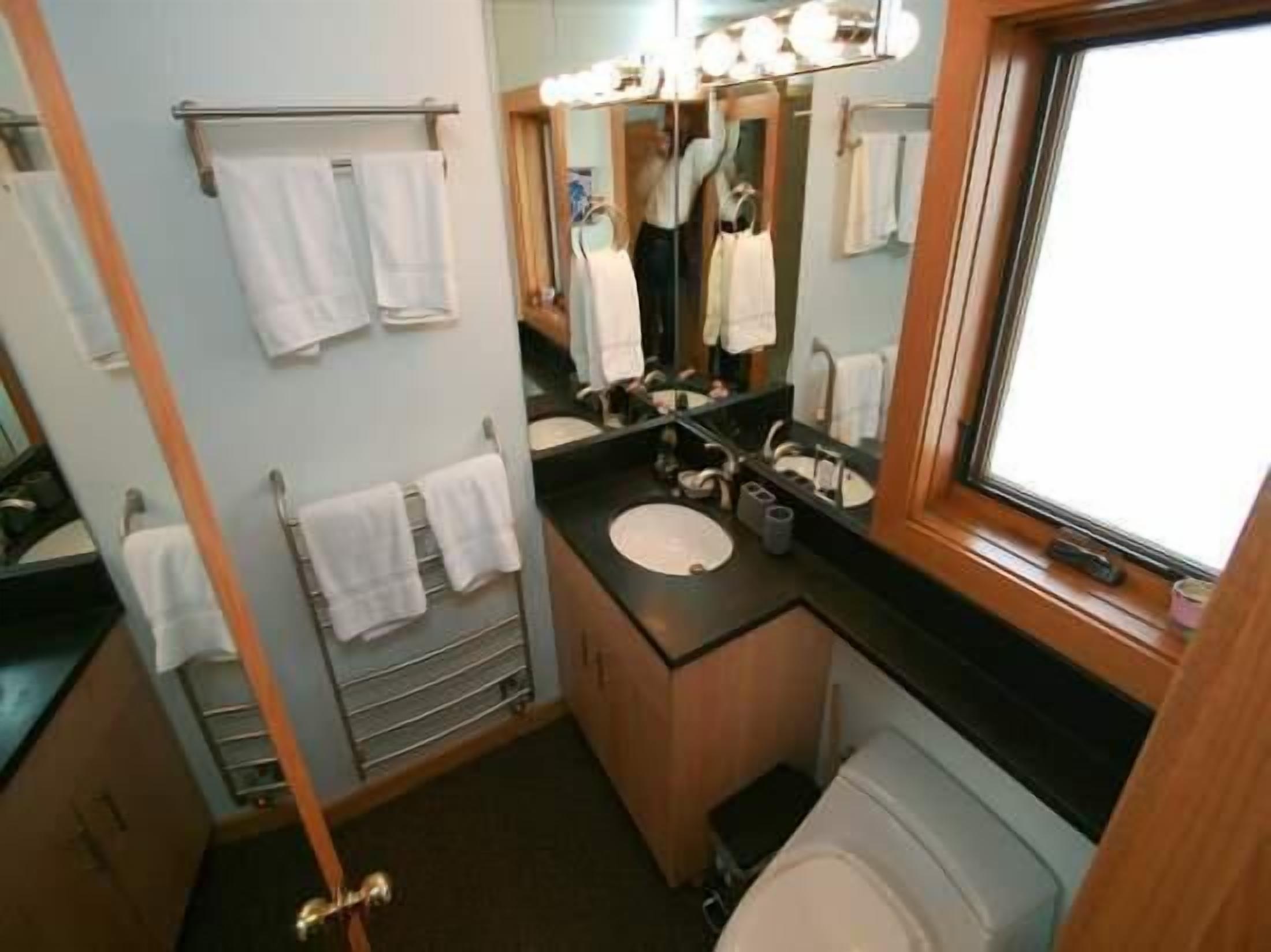 A compact bathroom with a sink, mirror, and towel rack.