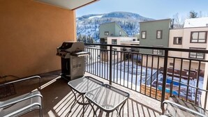 A balcony with a grill, two metal chairs, and a view of buildings and mountains. - Breakaway West Ski Condo 1,5 miles from the Lifts by RedAwning (Vail)