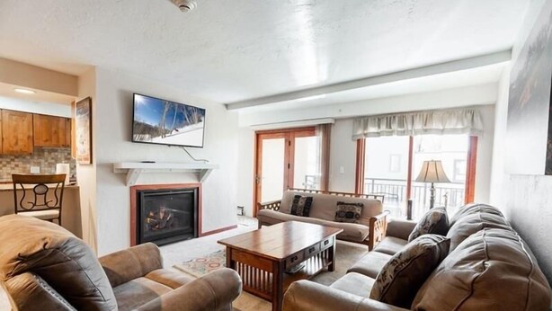 A living room with a fireplace, sofa, and television. - Breakaway West Ski Condo 1,5 miles from the Lifts by RedAwning (Vail)