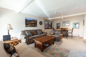 A living room with a sofa, armchair, coffee table, and a dining area with a table and chairs. - Breakaway West Ski Condo 1,5 miles from the Lifts by RedAwning (Vail)