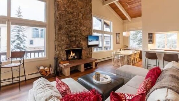 Una sala de estar acogedora con chimenea de piedra, un televisor y un comedor con mesa y sillas.