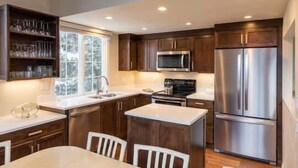 Una cocina moderna con armarios de madera, electrodomésticos de acero inoxidable y encimera blanca.