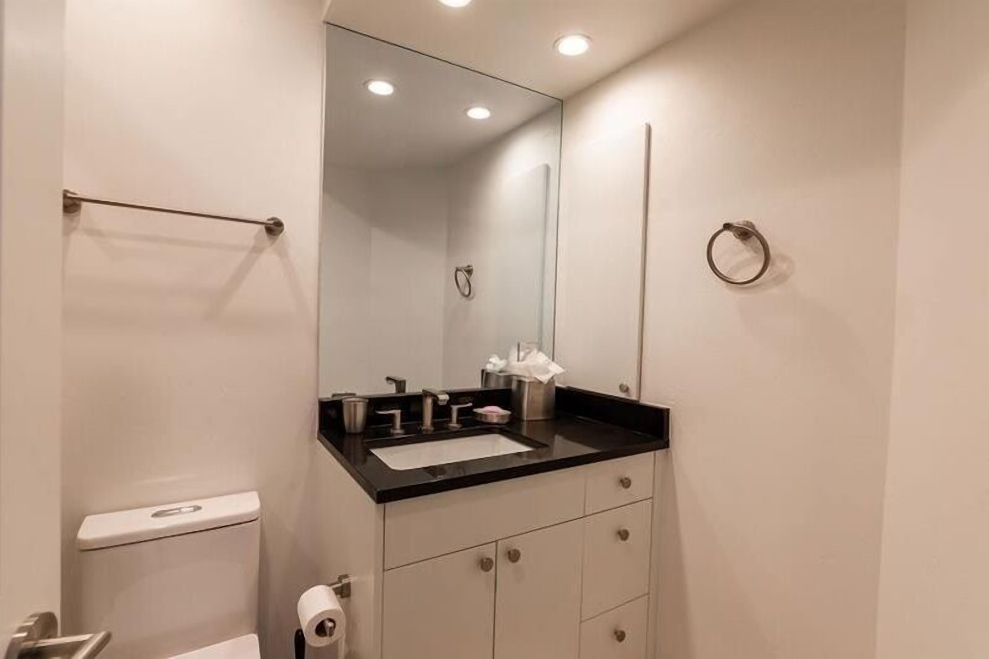 A modern bathroom with a black countertop sink, a mirror, and a toilet.