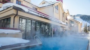 Ein Poolbereich mit Whirlpool, umgeben von einem Gebäude mit großen Fenstern und einer verschneiten Landschaft im Hintergrund.