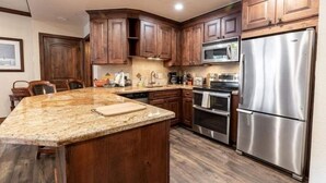 Eine Küche mit Holzschränken, Edelstahlgeräten und einer Arbeitsplatte aus Granit.