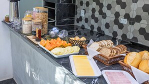 A buffet with various food items including fruits, cheeses, breads, and condiments. - Pousada In Bali (São Sebastião)