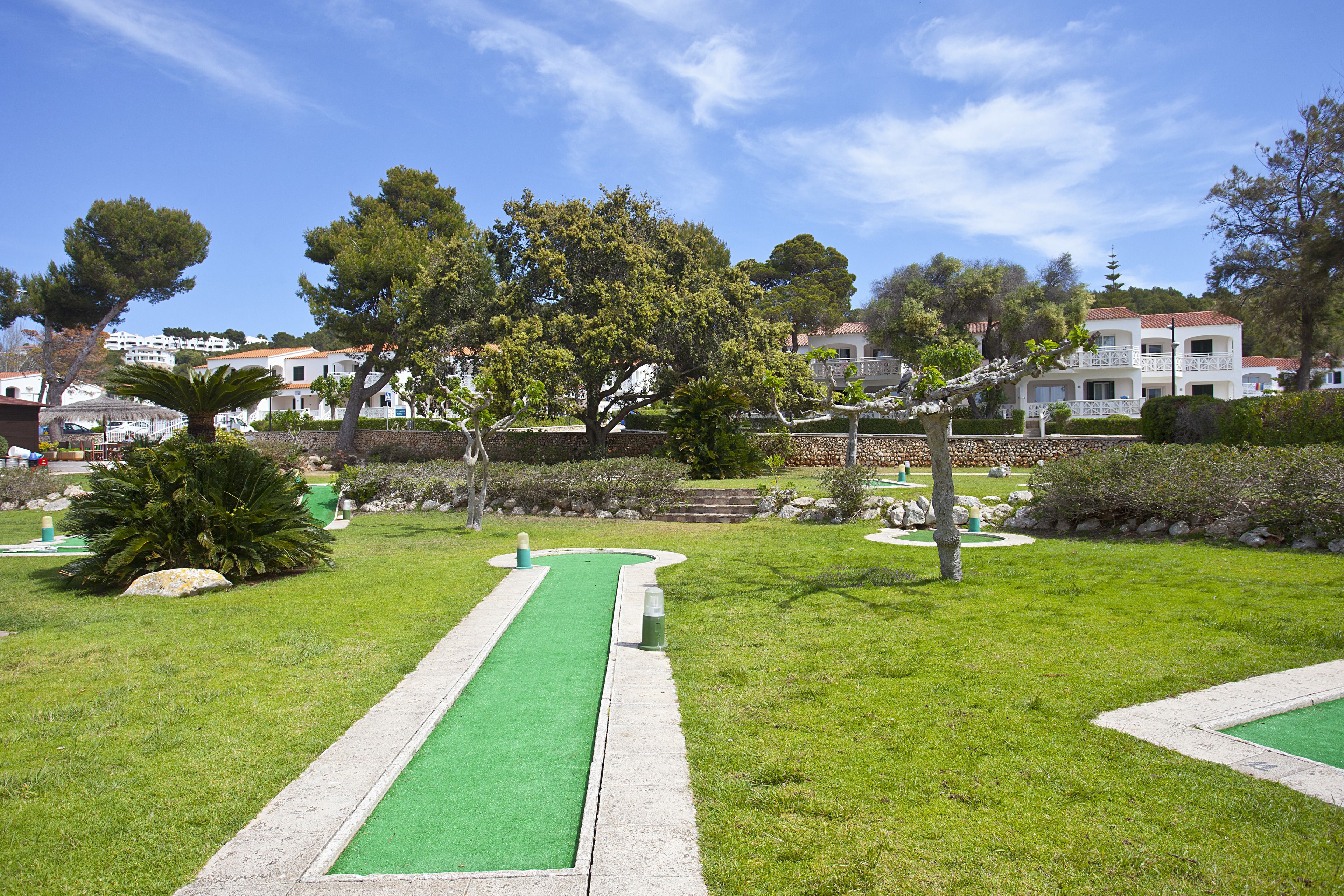 Ein Golfplatz mit einer grünen Spielbahn, Bunkern und einem Putting-Green.