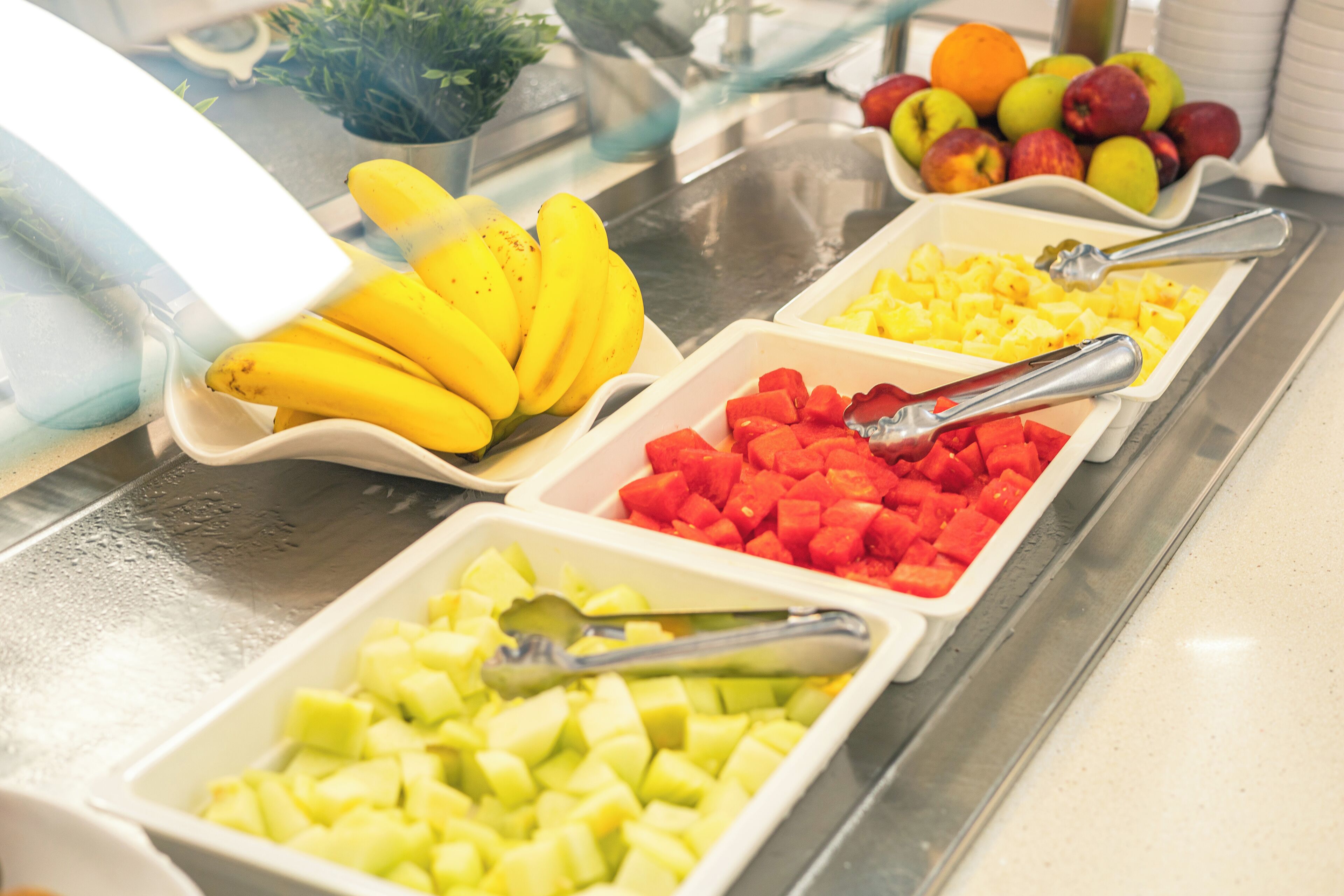 Un buffet con diversi tipi di frutta, tra cui banane, mele e anguria.