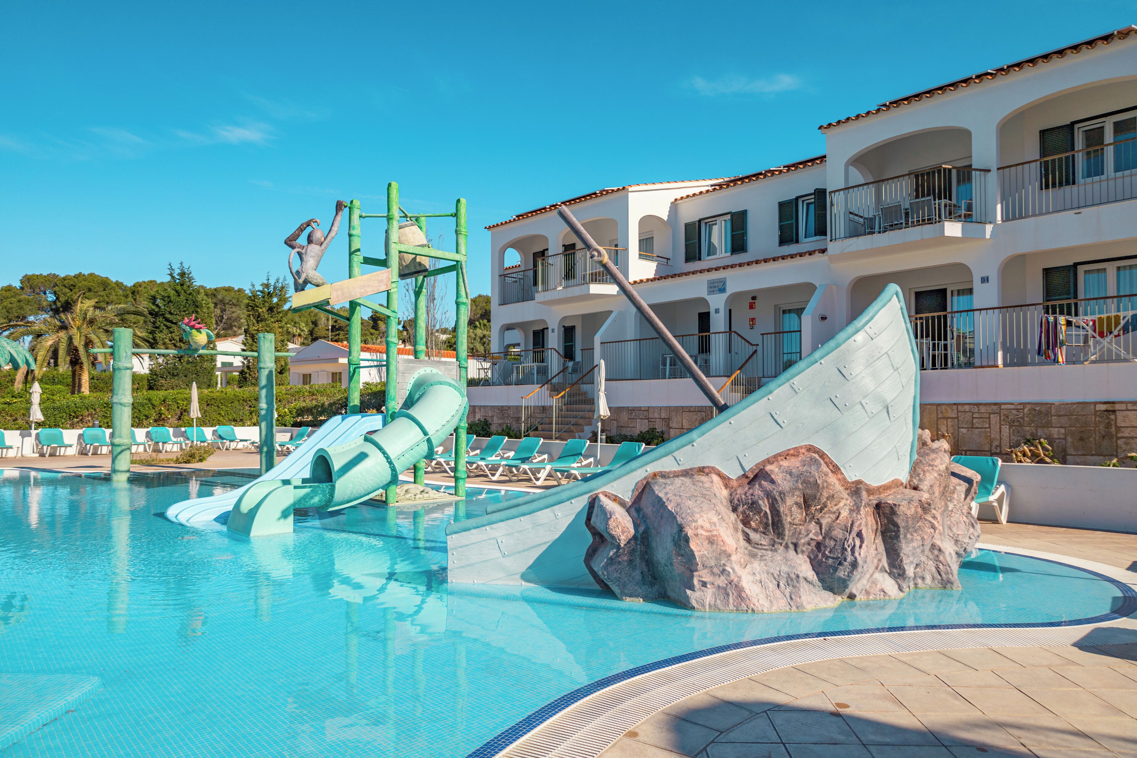 Una piscina con tobogán y formaciones rocosas.