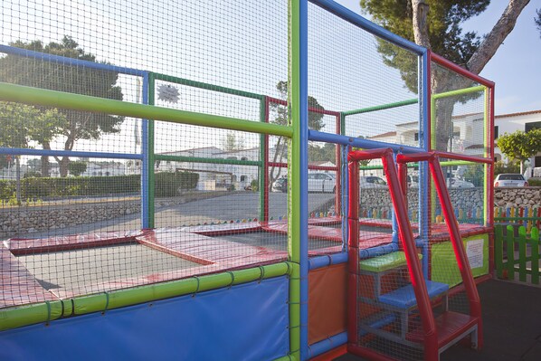 Estructura de juegos infantiles con cerramiento de red y equipo lúdico colorido.