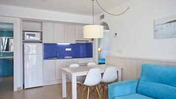 Una cocina moderna con armarios blancos, una encimera azul y un comedor con mesa y sillas blancas.