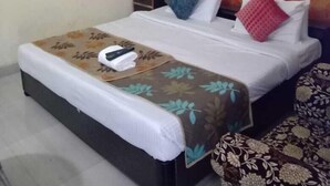 Ein Hotelzimmer mit einem Bett, einem Nachttisch, einer Wand-Klimaanlage und einem Gemälde.
