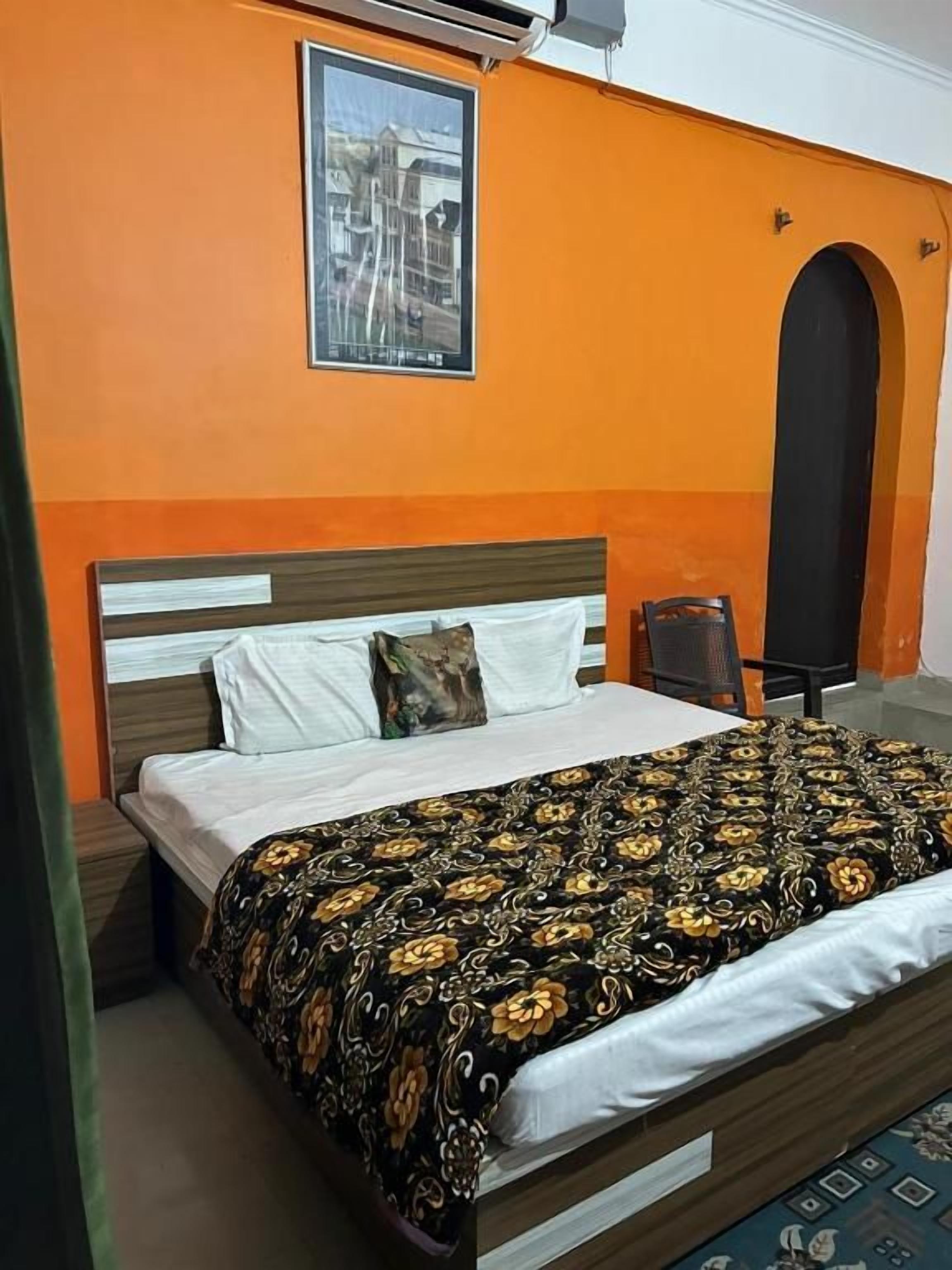 A room with a bed, a nightstand, a chair, and a poster on the wall.