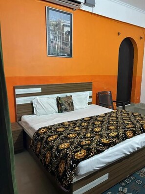 A room with a bed, a nightstand, a chair, and a poster on the wall. - Hotel Blue Star By Amazone Holidays (Haldwani)