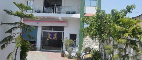 A two-story building with a balcony, a restaurant sign, and potted plants.