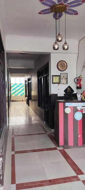 A hotel reception area with a reception desk, a clock, and a fire extinguisher. - Hotel Blue Star By Amazone Holidays (Haldwani)