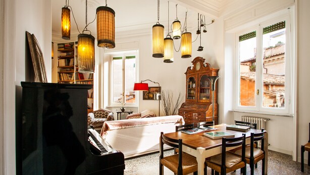 A cozy living room with a piano, wooden dining table, and a large cabinet. - Wanderlust, 3 Bedroom Air Conditioned Apartment in Trastevere (Rome)