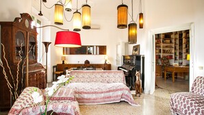 A cozy living room with a patterned sofa, a red lamp, and a bookshelf filled with books. - Wanderlust, 3 Bedroom Air Conditioned Apartment in Trastevere (Rome)