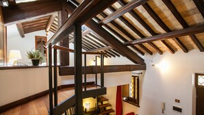 A multi-level interior with wooden beams, a staircase, and a seating area with red chairs. - Cozy Apartment in via dei Cappellari, Campo de' Fiori (Rome)