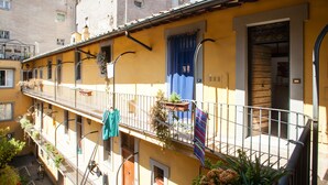 A yellow building with a balcony, a wooden door, and a blue curtain. - Cozy Apartment in via dei Cappellari, Campo de' Fiori (Rome)