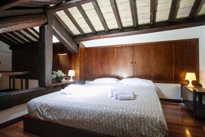 A bedroom with a large bed, wooden wardrobe, and a skylight.