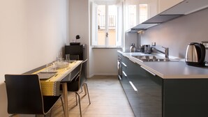 A modern kitchen with a dining area, featuring a window, stainless steel appliances, and a clean, minimalist design. - Cozy Apartment in via Degli Spagnoli, Pantheon (Rome)