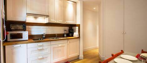 A modern kitchen with white cabinets, a microwave, and a dining area with a table set for two.