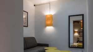 Una sala moderna con tragaluz, un sofá, dos mesitas auxiliares amarillas y una alfombra de estampado geométrico.