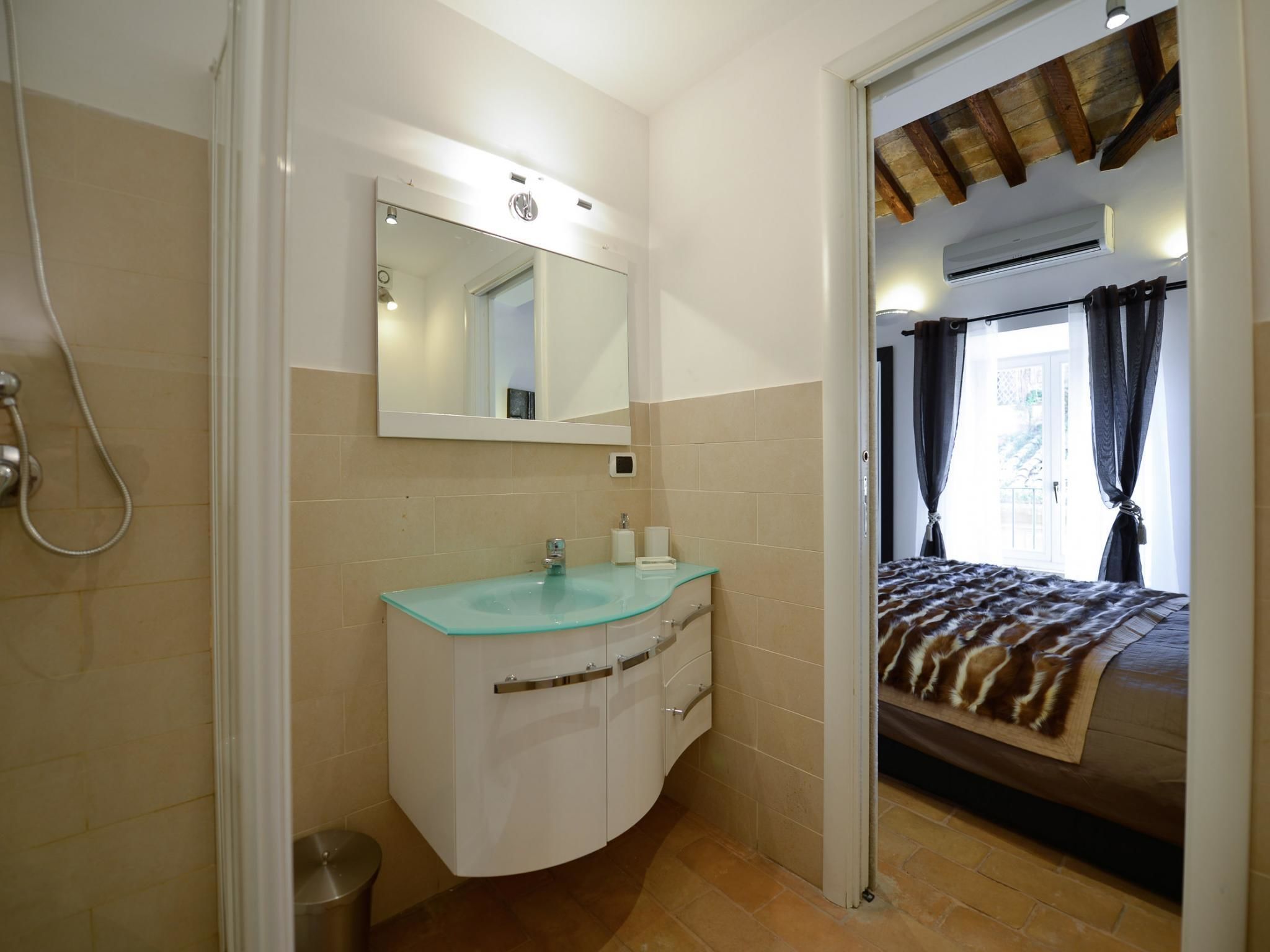 Un baño con lavamanos de vidrio, espejo y ducha.