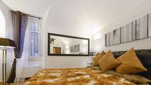 Un dormitorio con una cama grande, un espejo y un ventanal con cortinas.