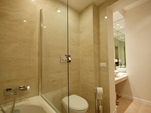 Un baño moderno con ducha de vidrio, bañera y retrete.