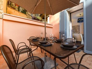 A dining area with a table set for four, surrounded by chairs, under a large umbrella. - Spagna Apartment (Rome)