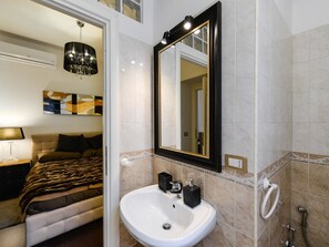 A modern bathroom with a white sink, a mirror with a black frame, and a shower area. - Spagna Apartment (Rome)