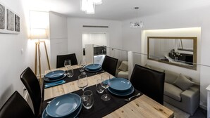 Un espace repas moderne avec une table en bois pouvant accueillir six personnes, des chaises noires et une cloison en verre.
