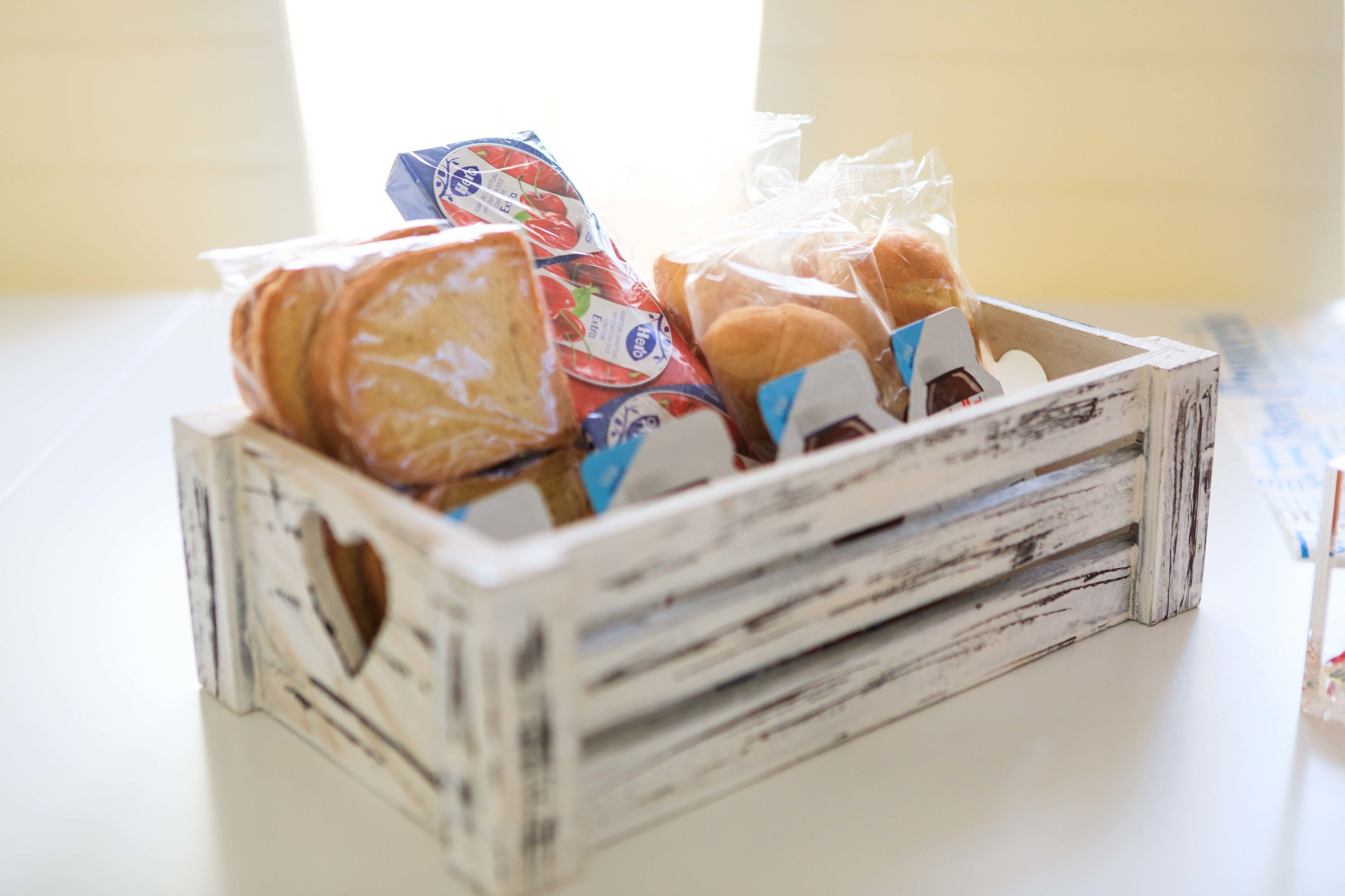 A rustic wooden crate filled with various packaged food items, including bread and dairy products.