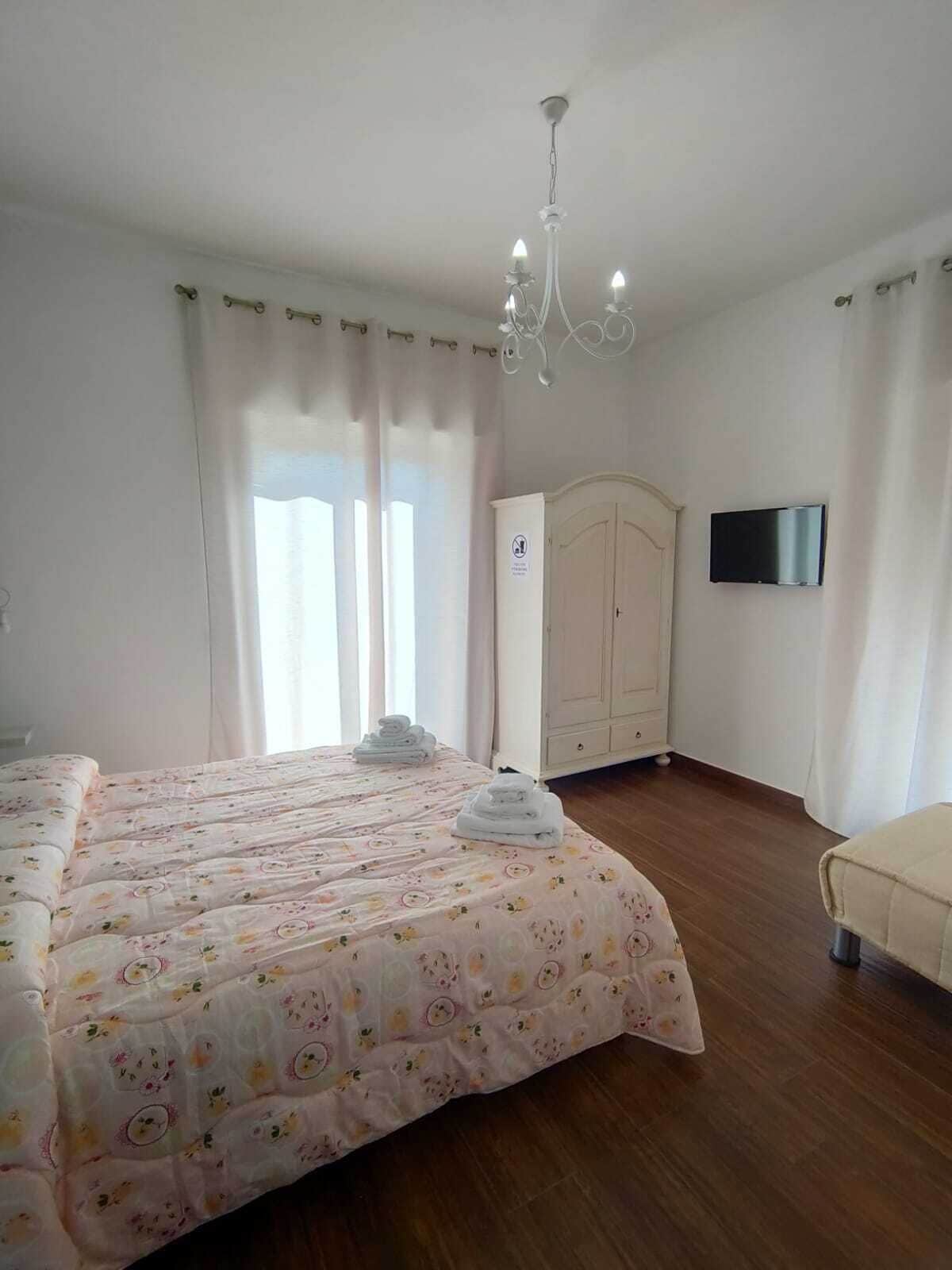 Ein Schlafzimmer mit Bett, Kleiderschrank, Fernseher und einer Chandelier.